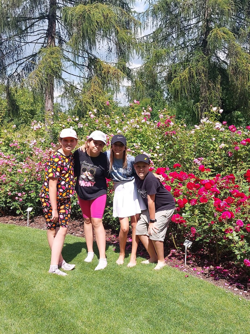 Aflopark czwórka dzieci pozuje do zdjęcia przy kwitnących krzewach róż